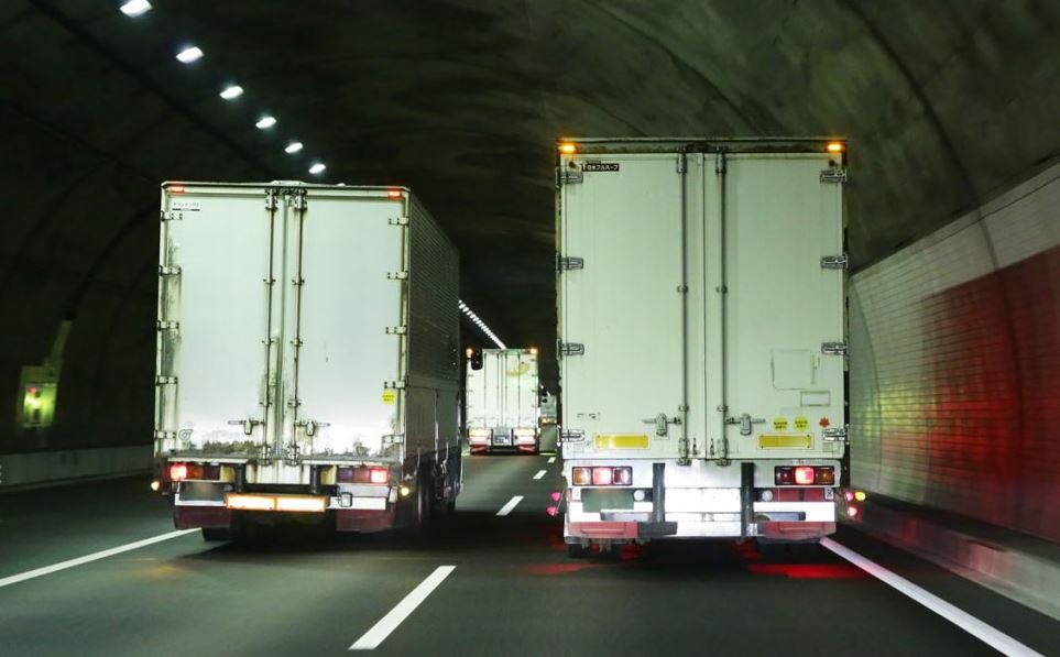 Camions de transport routier circulant de nuit dans un tunnel autoroutier