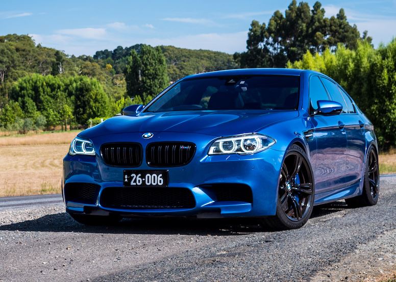 BMW M5 F10 bleue stationnée sur route de campagne