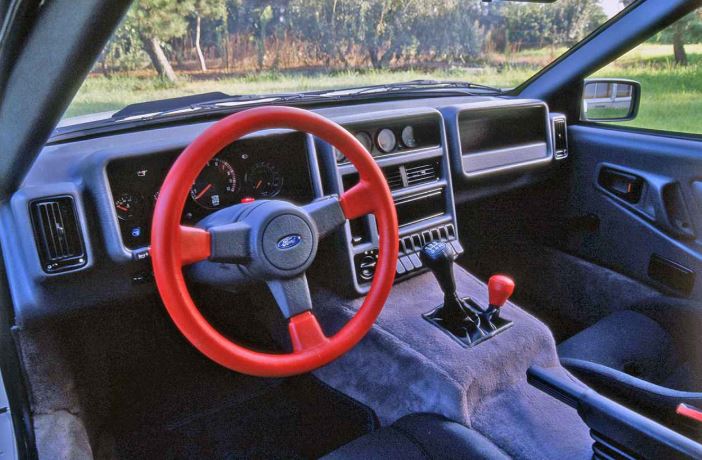 Intérieur minimaliste de Ford RS200 avec volant rouge et instrumentation rallye