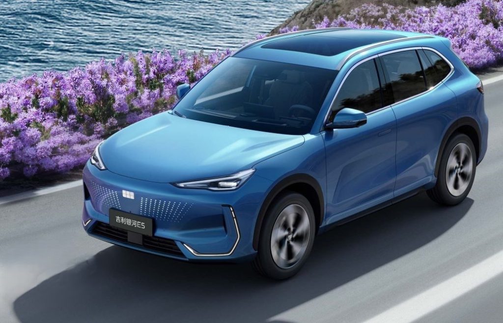 Geely E5 bleu sur route côtière vue plongeante