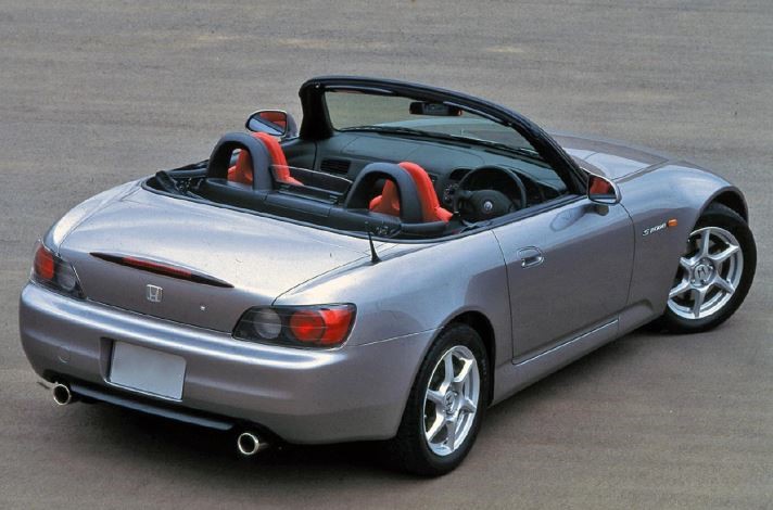 Honda S2000 grise décapotée vue de trois quarts arrière, avec sièges rouges et doubles sorties d’échappement.