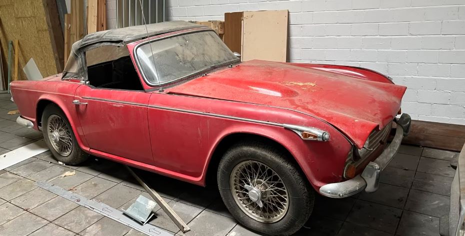 Triumph TR4 IRS rouge poussiéreuse stockée dans un garage avant restauration