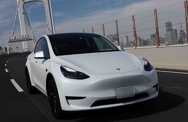 Tesla Model Y blanche vue avant sur route urbaine avec skyline moderne