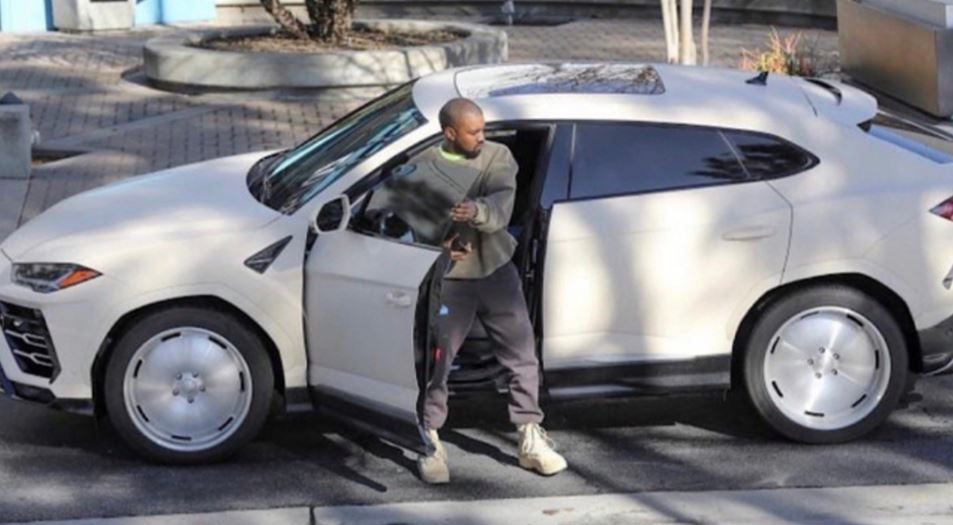 Kanye West sortant d’un Lamborghini Urus blanc devant une résidence