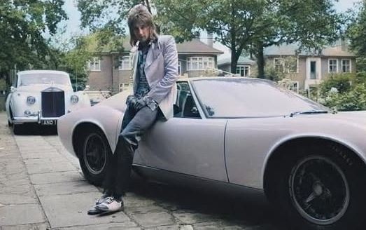 Rod Stewart appuyé sur sa Lamborghini Miura avec une Rolls-Royce en arrière-plan