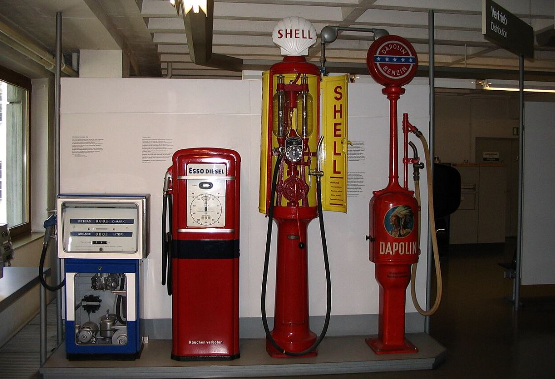 Collection d'anciennes pompes à essence exposées dans un musée, illustrant l'évolution de la distribution de carburant au fil des décennies.