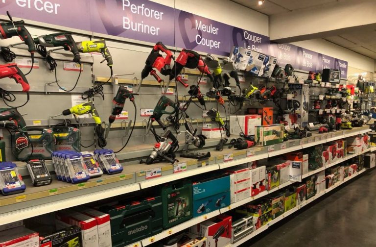 Rayon de magasin de bricolage présentant des outils électroportatifs de différentes gammes, illustrant le choix entre prix d'achat, qualité et durabilité des équipements.