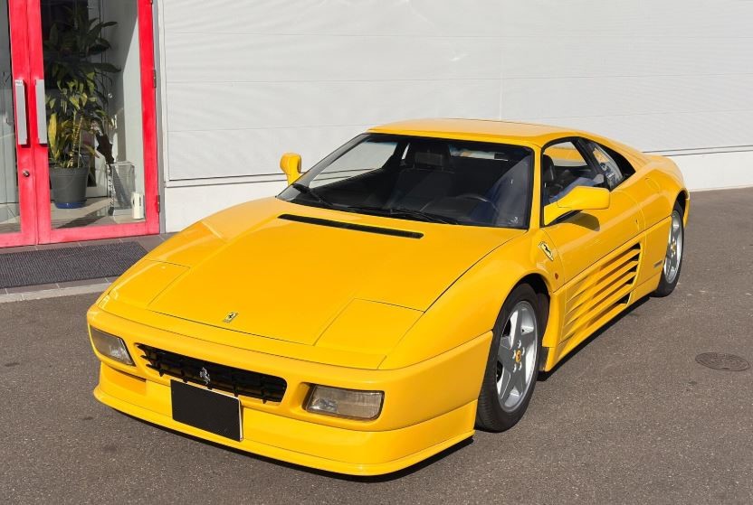 Ferrari 348 jaune stationnée montrant le design inspiré de la Testarossa