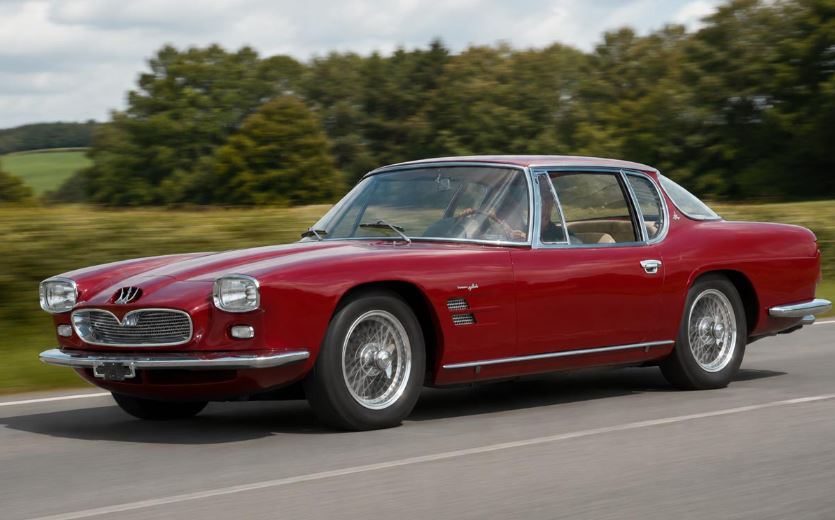 Maserati 5000 GT Frua rouge en circulation sur une route de campagne