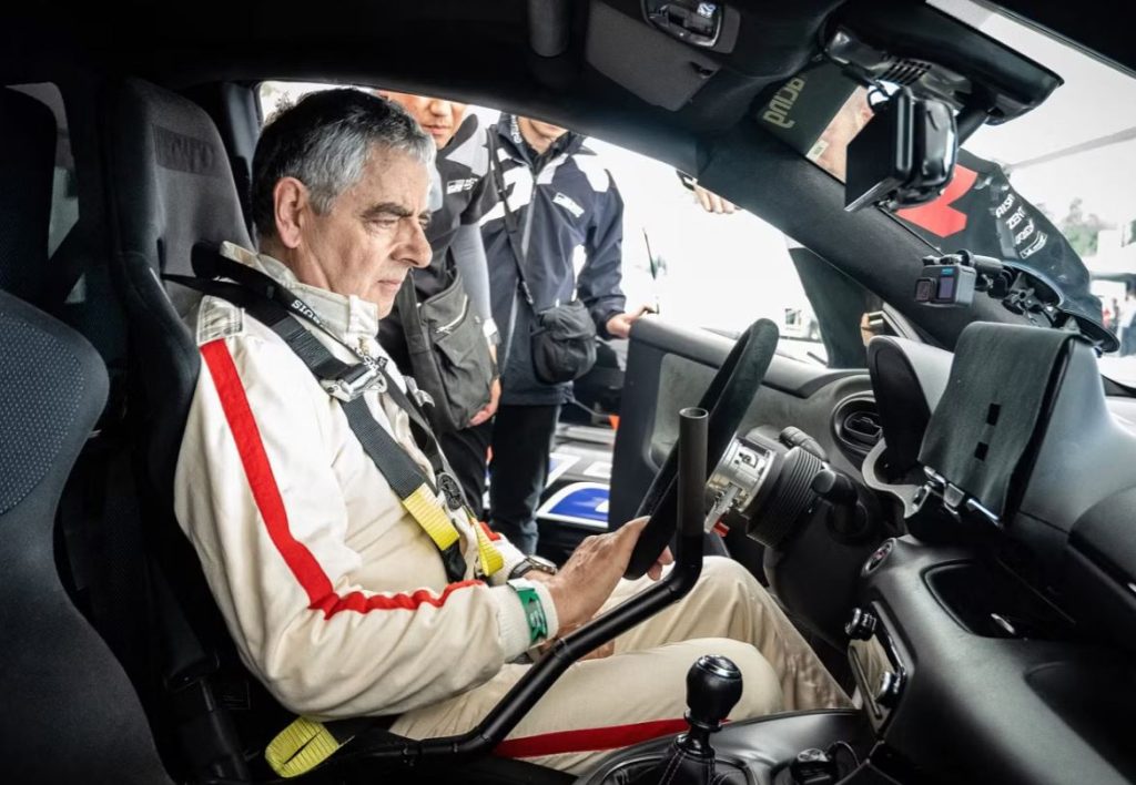 Rowan Atkinson installé dans le cockpit d'une Toyota GR lors d'un événement automobile