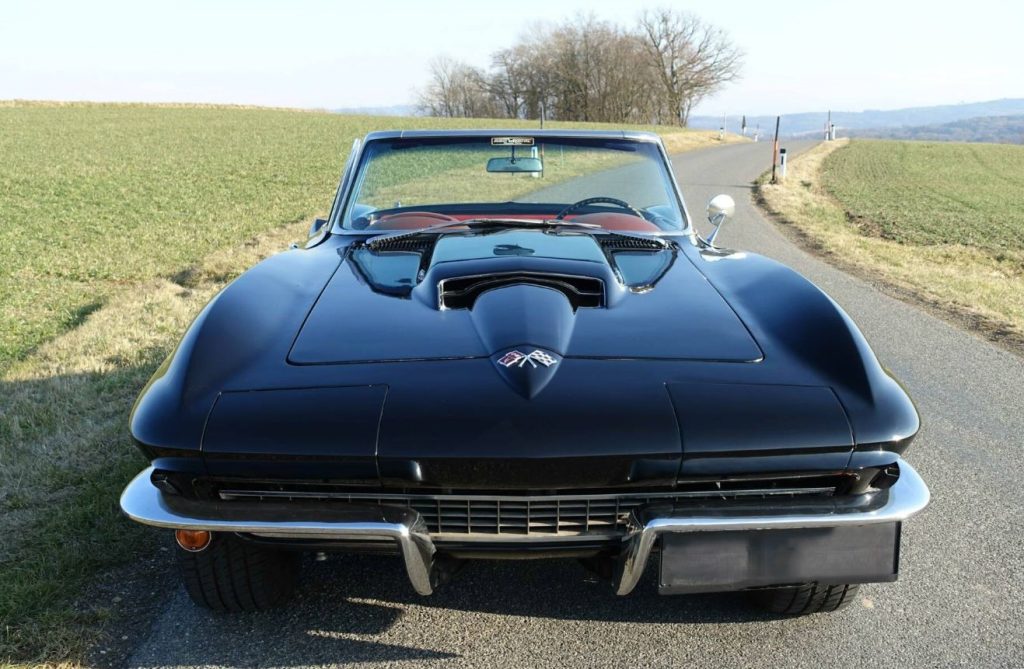 Chevrolet Corvette C2 noire des années 1960 photographiée sur une route de campagne