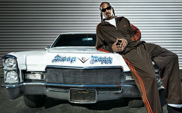 Snoop Dogg posé devant sa Cadillac DeVille personnalisée inspirée de la culture lowrider