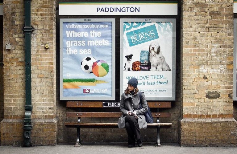 Personne assise sur un banc dans une gare, illustrant le temps d'attente dans les transports du quotidien.