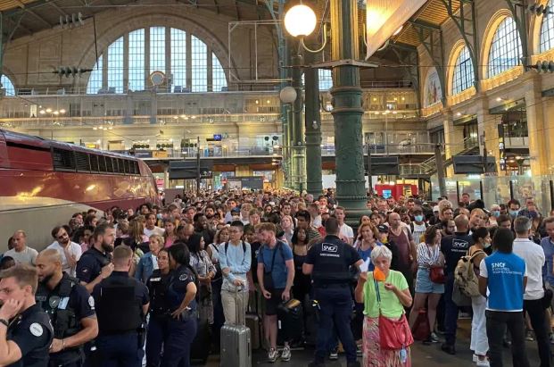 Voyageurs rassemblés dans une gare après un retard de train, illustration de l'attention portée aux événements inhabituels.