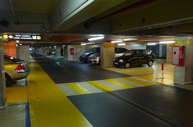 Parking souterrain de centre commercial avec places de stationnement et allées de circulation étroites.