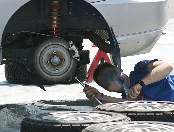 Mécanicien réalisant une réparation sous un véhicule, illustration des difficultés croissantes pour réparer une voiture moderne.