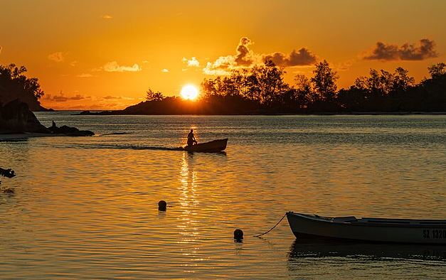 Coucher de soleil sur un plan d'eau avec une barque, une scène propice à l'émerveillement devant la nature.