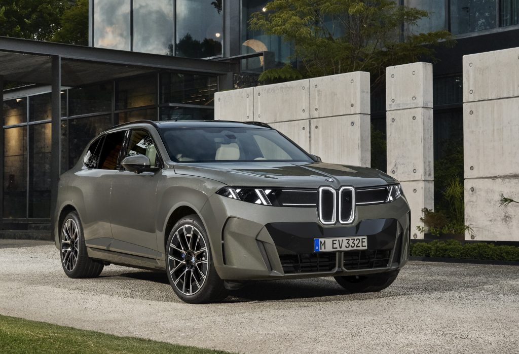 BMW X5 2027 présenté de trois quarts avant devant un bâtiment moderne