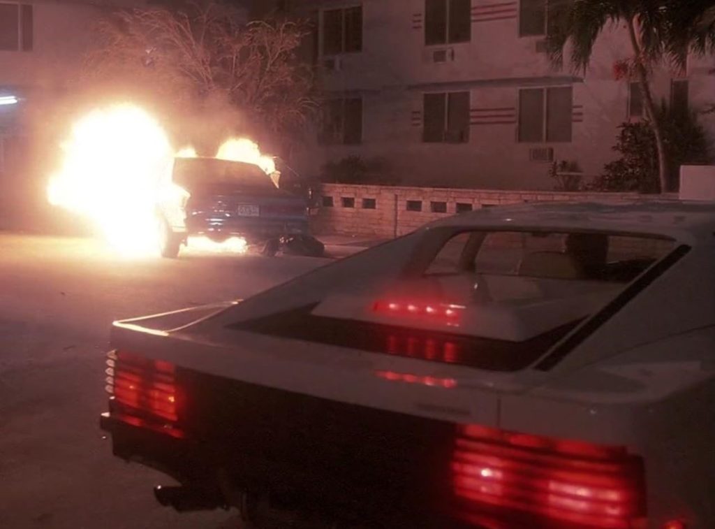 Ferrari Testarossa de Miami Vice lors d'une scène nocturne avec un véhicule en flammes