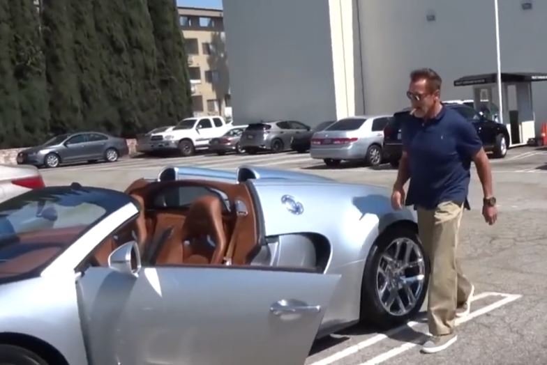 Arnold Schwarzenegger au volant de sa Bugatti Veyron devant un parking à Los Angeles