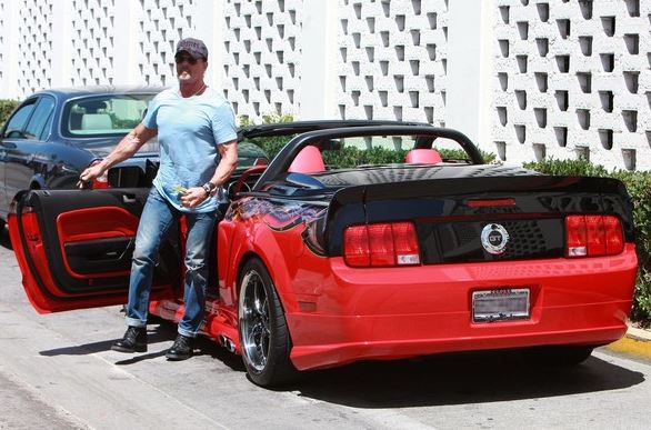 Sylvester Stallone aux côtés d'une Ford Mustang GT cabriolet rouge