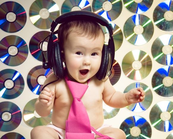 Bébé souriant avec un casque audio, illustration du lien entre musique et bonne humeur.