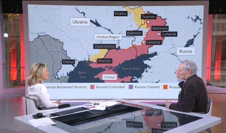 Expert invité sur un plateau de télévision devant une carte de la guerre en Ukraine.