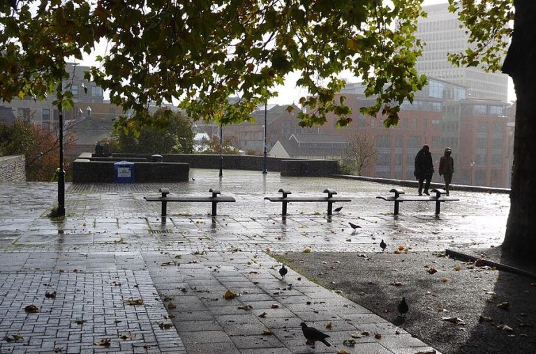 Place urbaine sous une forte pluie, illustrant une eau de pluie encore trop peu récupérée pour les usages du quotidien.