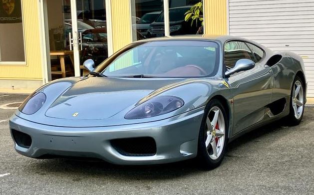 Ferrari 360 Modena gris argent vue de trois quarts avant devant un showroom