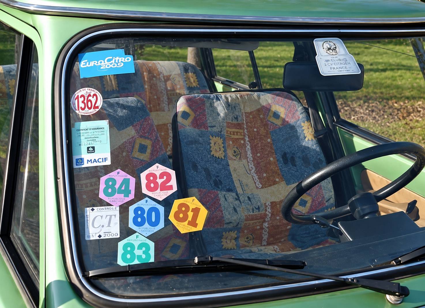 Anciennes vignettes automobiles françaises apposées sur le pare-brise d’une voiture.