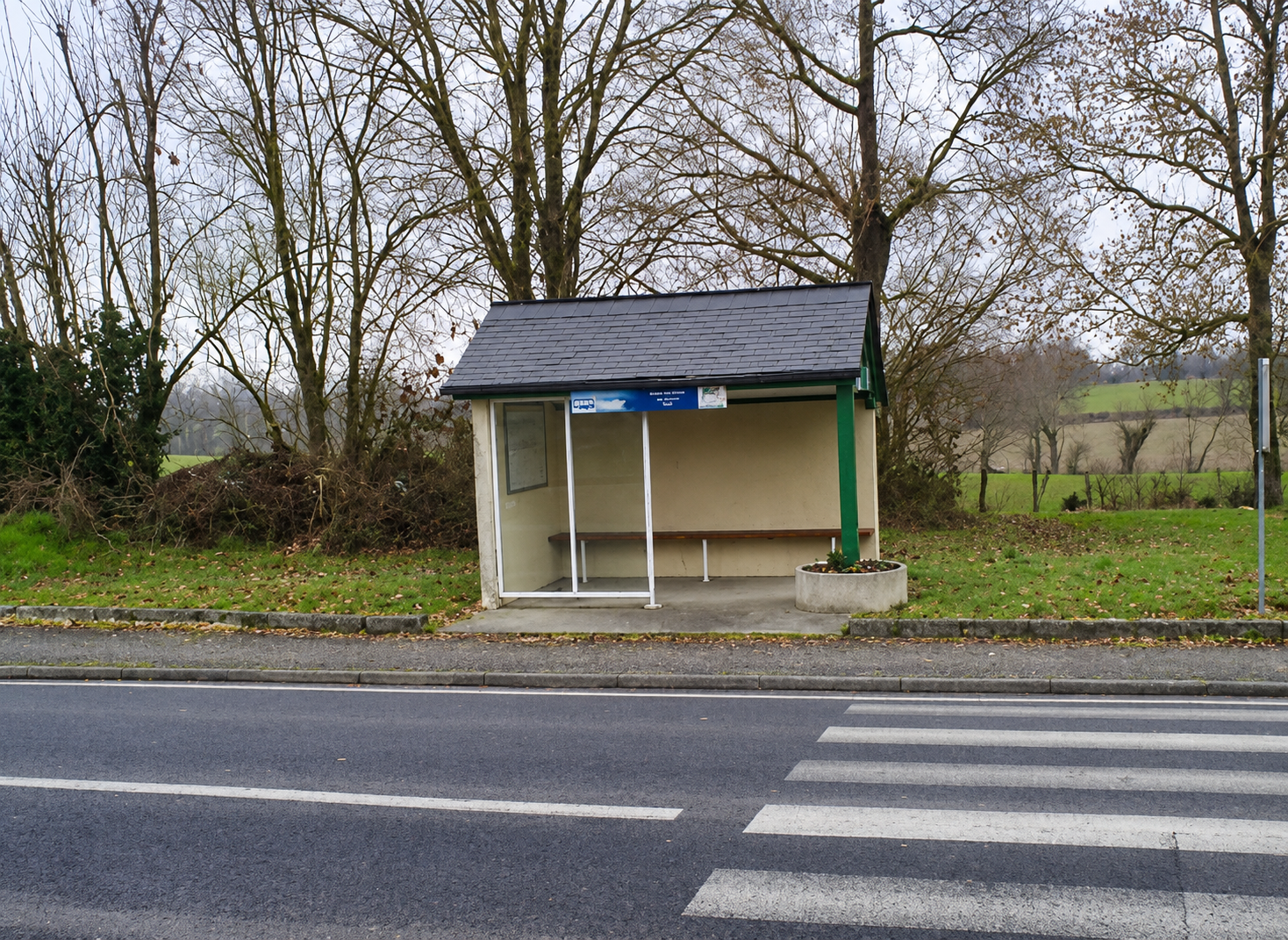 Arrêt de bus vide en zone rurale, illustration des difficultés de mobilité pour accéder à l'emploi.