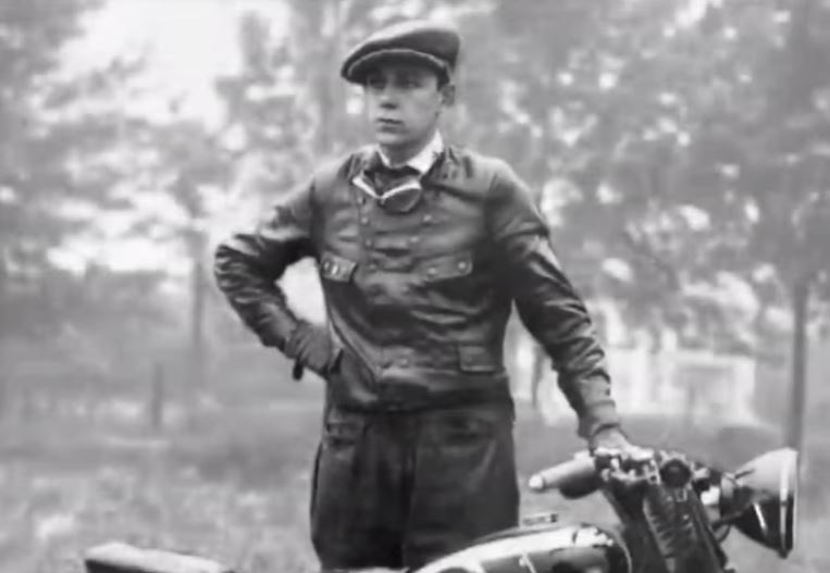 Jeune Carlo Abarth en tenue de pilote aux côtés de sa moto