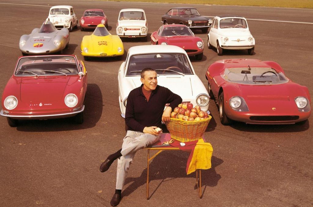 Carlo Abarth entouré de voitures Abarth avec un panier de pommes