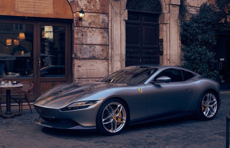 Ferrari Roma grise vue de trois quarts avant dans une rue de Rome, devant un café italien.