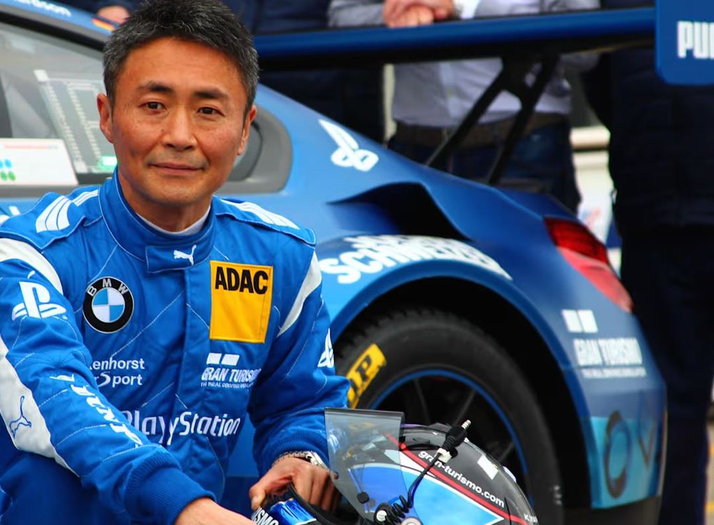 Kazunori Yamauchi en combinaison de pilote aux couleurs Gran Turismo et PlayStation