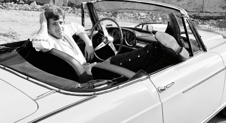 Jean-Paul Belmondo dans un cabriolet, illustrant sa passion pour les voitures