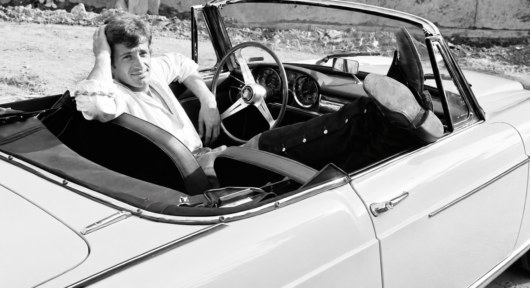 Jean-Paul Belmondo dans un cabriolet, illustrant sa passion pour les voitures