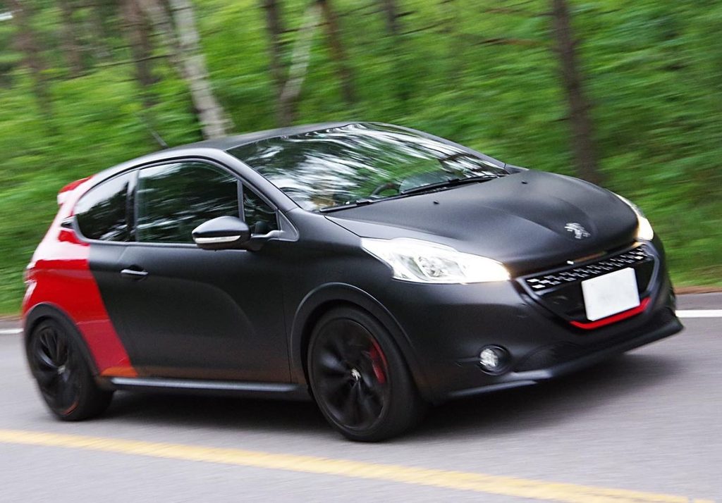 Peugeot 208 GTI noire et rouge en mouvement