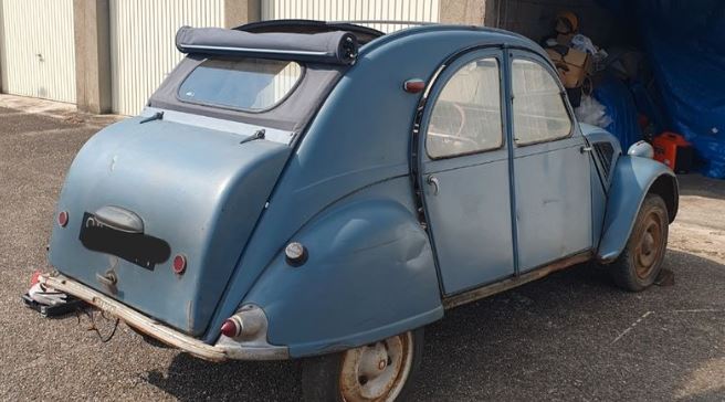 Citroën 2 CV bleue de 1955 à malle bombée lors d’une sortie de grange