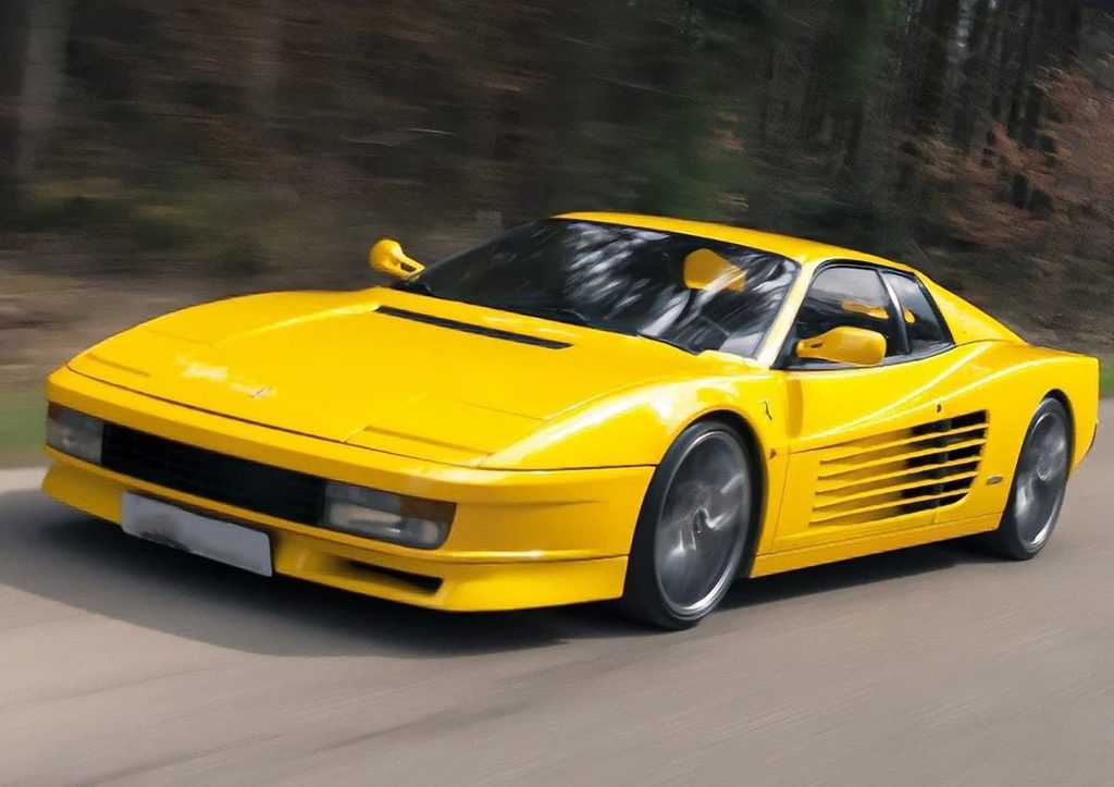 Ferrari Testarossa jaune photographiée en mouvement, avec ses prises d'air latérales striées caractéristiques.