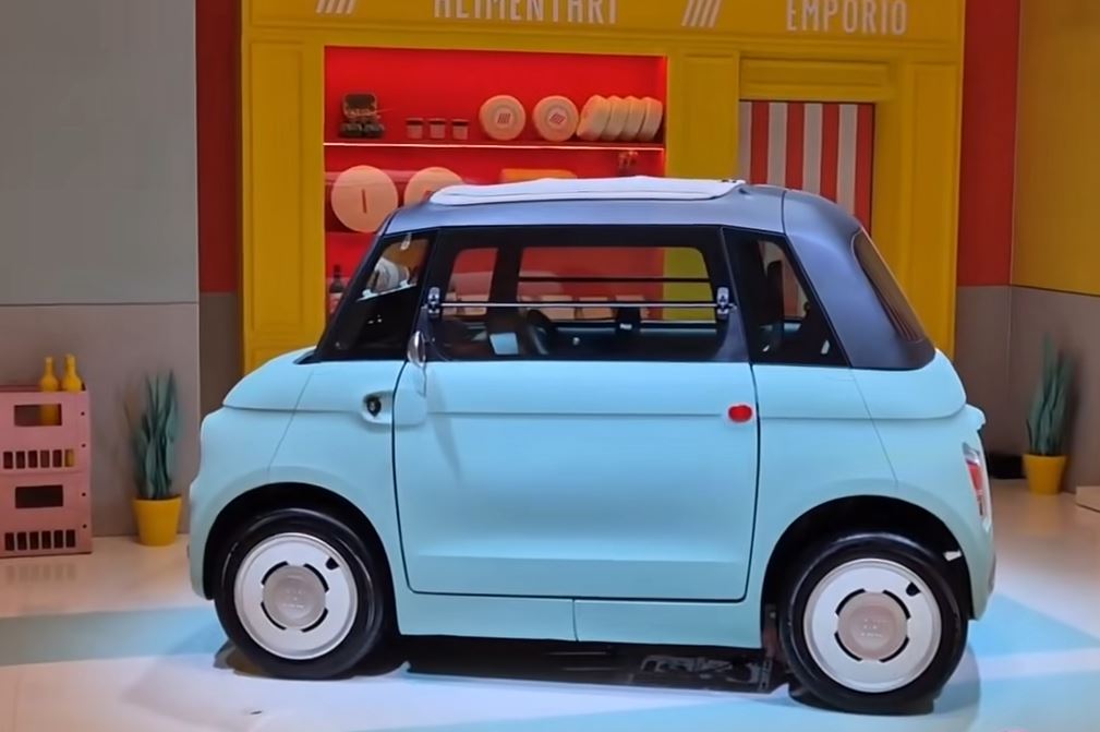 Fiat Topolino électrique bleu clair vue de profil, quadricycle léger à deux places présenté sur un stand Fiat.