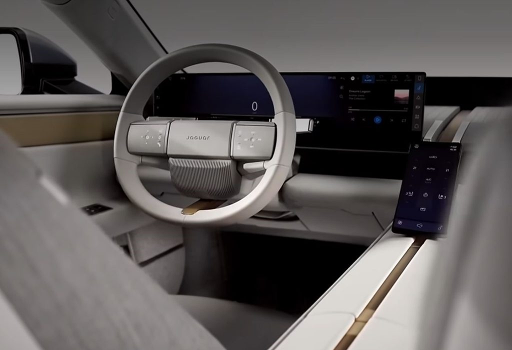 Intérieur de la Jaguar Type 01 avec volant blanc, instrumentation numérique et écrans de commande.