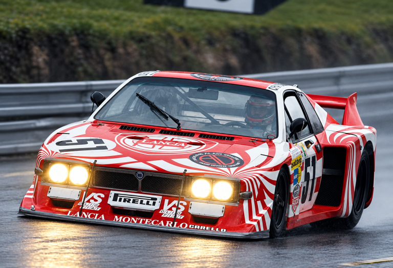 Lancia Beta Montecarlo Turbo Groupe 5 numéro 51 en course sur circuit mouillé, phares allumés.
