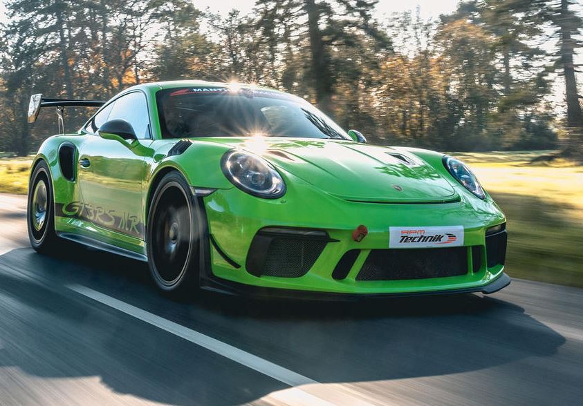 Porsche 911 GT3 RS génération 991 verte photographiée en mouvement sur route, avec son grand aileron arrière.