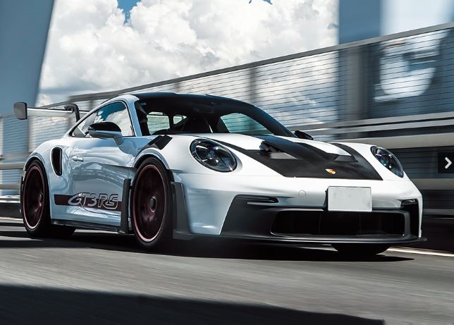 Porsche 911 GT3 RS 992 blanche en mouvement, vue de trois quarts avant avec son aérodynamique de circuit.