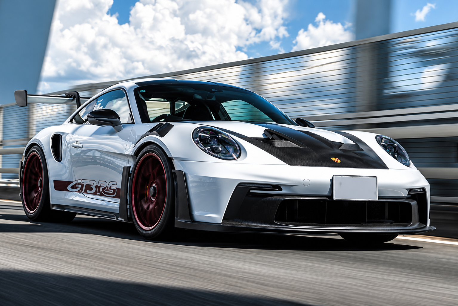 Porsche 911 GT3 RS 992 blanche en mouvement, vue de trois quarts avant avec son aérodynamique de circuit.