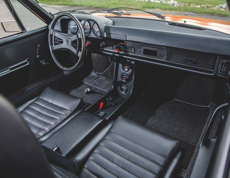 Habitacle d'une Porsche 914 2.0 avec tableau de bord noir, trois compteurs, sièges baquets et levier de vitesses manuel.