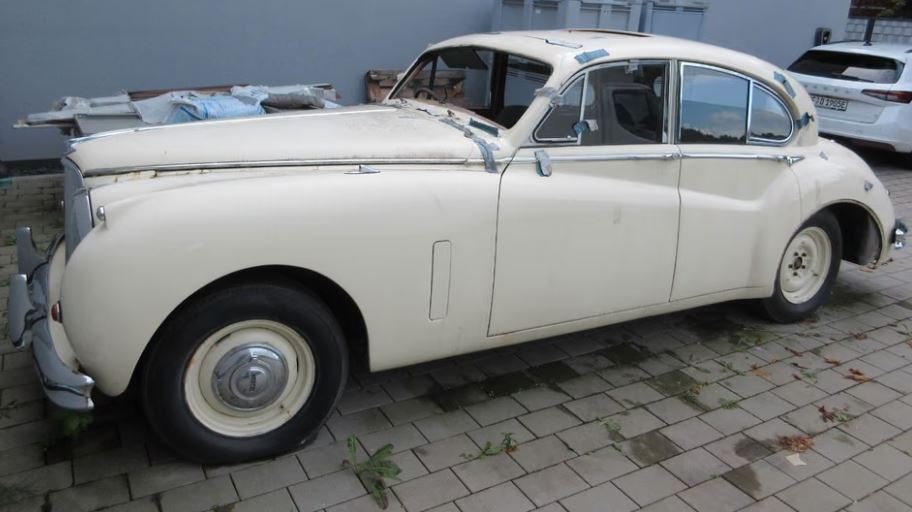 Jaguar MK VIII de 1957, berline britannique blanche en attente de restauration, avec ses chromes et sa carrosserie arrondie.