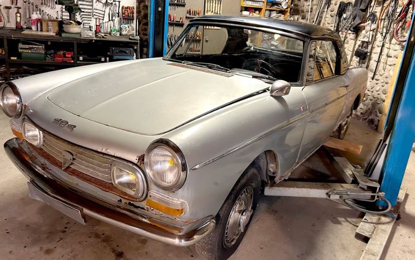 Peugeot 404 cabriolet de 1968 dans un atelier, avec sa carrosserie ancienne et ici son hard top noire
