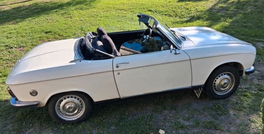 Peugeot 304 S Cabriolet de 1974 blanc crème, capote repliée, photographié de profil sur une pelouse.
